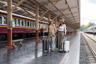 Hafta sonu seyahati sırasında tren istasyonunda bekleyen bir bavul tutan genç kadın...