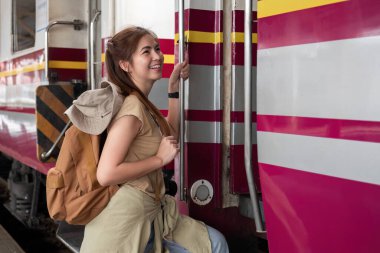 Sırt çantası taşıyan genç bir kadın hafta sonu seyahati sırasında tren istasyonunda tren bekliyor...