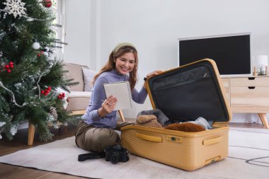 Çekici Asyalı kadın tatile çıkmadan önce bavulunu topluyor, eşyalarını, elbiselerini ve seyahat belgelerini topluyor. Yaşam tarzı kavramı.