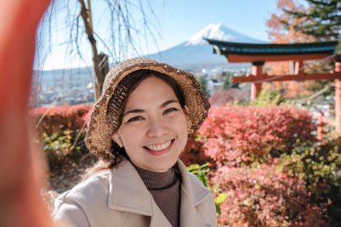 Şapka takan neşeli Asyalı kadın turist Japonya 'da arka planda selfie çekiyor..