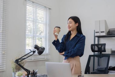 Portre gülümseyen Asyalı iş kadını finansal işlemler için dizüstü bilgisayar kullanıyor. Ofisteki masada planlama işi..
