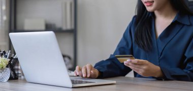 Kredi kartı tutan ve bilgisayarını online alışveriş yapan genç bir kadın ya da mali durumunuzu internetten planlayan..