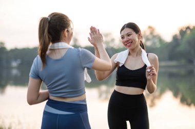 Spor giyimli güzel Asyalı kadın parkta koşuyor ya da koşuyor. Sağlığına dikkat etmek ve güçlü olmak için..