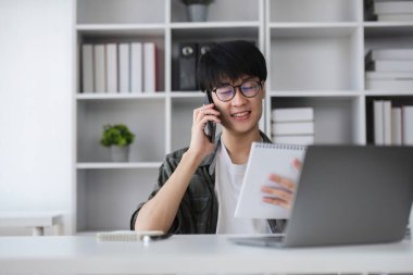 Genç Asyalı adam finansal yönetim üzerinde çalışmak için dizüstü bilgisayar kullanıyor. Finansal işlemler ve çevrimiçi bankacılık kullanımı.