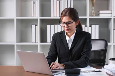 Genç Asyalı kadın bilgisayarını finansal işlem yapmak ve online bankacılık yoluyla finans ve yatırım planlamak için kullanıyor.