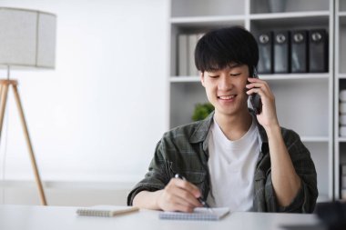 Genç Asyalı adam mali yönetim, mali işlemler ve çevrimiçi bankacılık kullanımı hakkında görüşmek için arıyor..