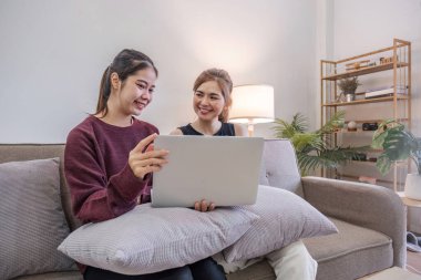 İki kadın, arkadaşları ve sınıf arkadaşlarıyla oturma odasında dizüstü bilgisayar ve akıllı telefon kullanarak iletişim kuruyor. Arkadaşlar, arkadaşlık, birlikte zaman geçirmek...