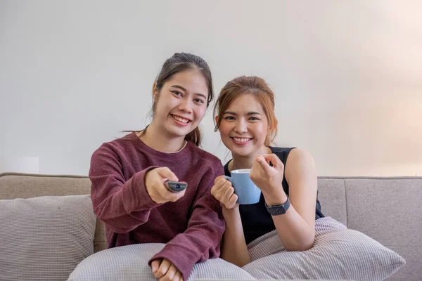 Two Asian sisters watch TV together. relax at home Enjoy watching television.