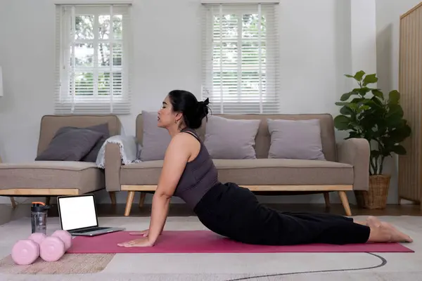 Fat Asian woman stretching at home on a fitness mat. Practicing activities at home online exercise classes Practice stretching on your yoga mat at home to stay healthy and in shape..