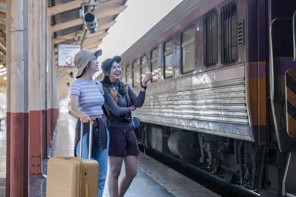 İki Asyalı bayan turist tren istasyonundalar. Hafta sonları trenle taşraya gitmek için bekliyorlar...