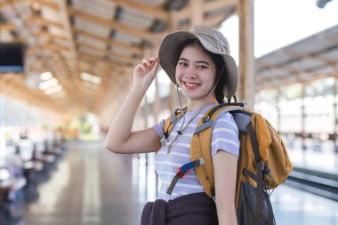 Tren istasyonunda bir bavul taşıyan sevimli Asyalı kadın treni bekliyor..