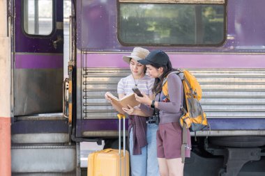 İki Asyalı bayan turist tren istasyonundalar. Hafta sonları trenle taşraya gitmek için bekliyorlar...