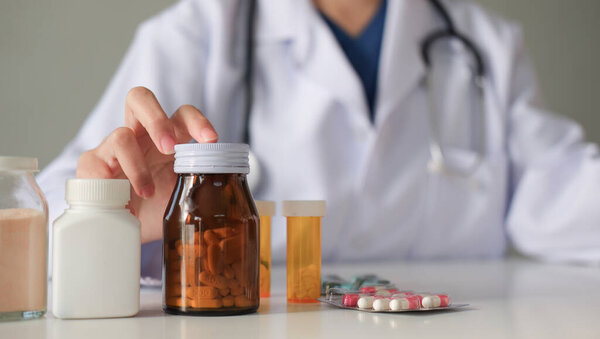Врач показывает рукой на бутылку с лекарством и дает советы по медицине...