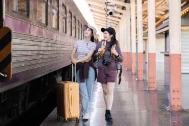 İki Asyalı bayan turist tren istasyonundalar. Hafta sonları trenle taşraya gitmek için bekliyorlar...