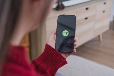 CHIANG MAI, THAILAND - 3 Ocak 2024: iPhone Xs açan kadın spotify uygulaması, Spotify yasal müzik sunan bir müzik servisidir..