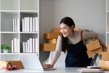 Startup small business entrepreneur SME, asian woman packing cloth in box. Portrait young Asian small business owner home office, online sell marketing delivery, SME e-commerce telemarketing concept.