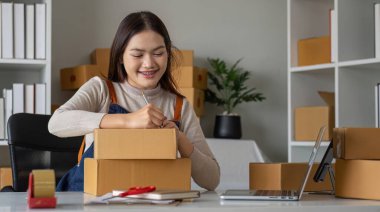 KME girişimcisi küçük işletme çevrimiçi satış konsepti, mutlu Asyalı iş sahibi evde bilgisayar ve kutular üzerinde çalışıyor, KOBİ satın alma paketi müşteri gönderme kutusu,.