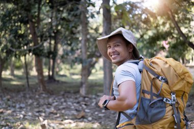 Mutlu gülümseyen Asyalı bir turistin portresi, 30-35 yaşlarında, ulusal parkta sırt çantasıyla geziyor. Asyalı erkek turist doğa aktivitelerinin, tatillerin, açık hava hobilerinin tadını çıkarıyor...