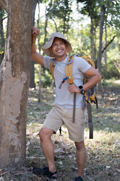 Portrait of a happy smiling Asian tourist, 30-35 years old, backpacking in a national park. asian male tourist enjoying his hiking trip Nature activities, holidays, outdoor hobbies..