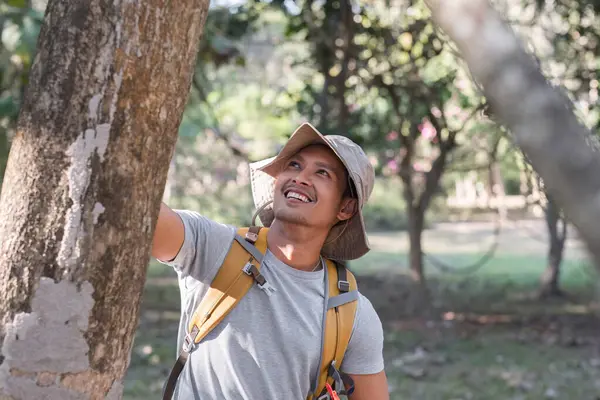 A middle-aged Asian tourist smiled happily. Backpacking in the national park Asian male tourist enjoying his hiking trip nature activities holiday outdoor activities.