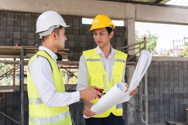 İnşaat mühendisleri ve ustabaşlarından oluşan bir ekip inşaat projesi planlarını tartışıyor. İnşaat alanında proje planı bekletiliyor.