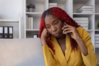 Ofiste stresle çalışırken telefonda konuşan Afrikalı Amerikalı iş kadını..