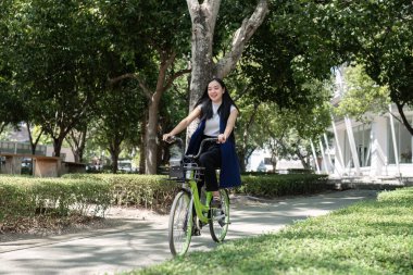 Asyalı iş kadını, hava kirliliğini azaltmak ve çevreyi korumak için ofise bisikletle gidiyor...