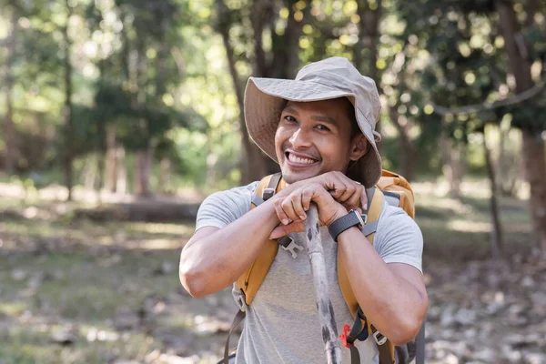 A middle-aged Asian tourist smiled happily. Backpacking in the national park Asian male tourist enjoying his hiking trip nature activities holiday outdoor activities.