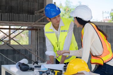 İnşaat mühendisi takımları modern kentteki inşaat sahasında birlikte çalışan işçi kaskı takıyorlar. Foreman Endüstri Mühendislik Mühendisliği ekip çalışması. Asya endüstrisi profesyonel takımı.
