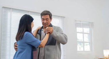 60 'lı yaşlarda yaşlı Asyalı bir çift oturma odasında dans ediyor, müzikten hoşlanıyor ve aşktan gülümsüyor...