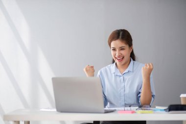Ofiste çalışan orta yaşlı mutlu bir iş kadını. İş kadını dizüstü bilgisayarda çalışıyor ve bilgisayardaki uzak online iş görüşmesinde kullanıyor..