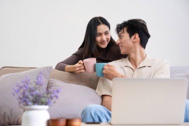 Genç Asyalı çift boş zamanlarını birlikte oturma odasında dinlenerek geçirir...