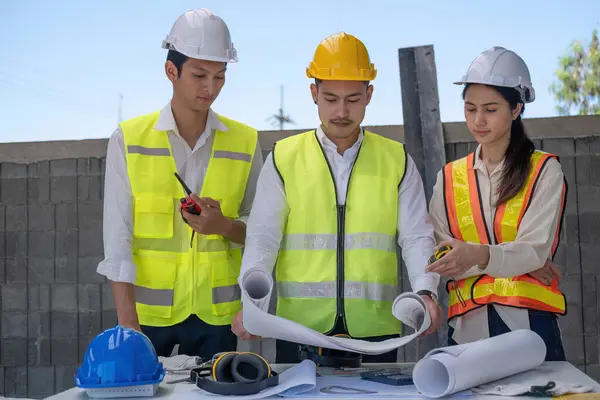 Civil engineer teams meeting working together wear worker helmets hardhat on construction site in modern city. Foreman industry project manager engineer teamwork. Asian industry professional team.