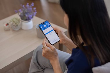 CHIANG MAI, THAILAND - 27 Şubat 2024: İphone 14 'ü elinde tutan kadın Facebook uygulaması ekranda. Facebook popüler bir online sosyal ağ hizmetidir..