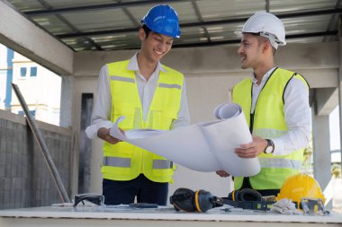 İnşaat mühendisi takımları modern kentteki inşaat sahasında birlikte çalışan işçi kaskı takıyorlar. Foreman Endüstri Mühendislik Mühendisliği ekip çalışması. Asya endüstrisi profesyonel takımı.