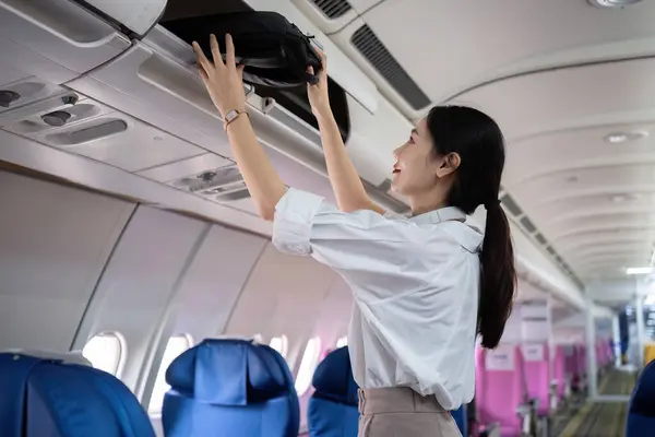 stock image Young woman traveling by plane put her bag in the luggage compartment of the plane..