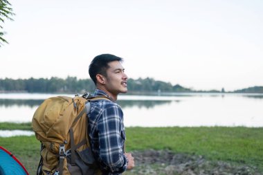 Asyalı turist mutlu bir şekilde sırt çantasıyla geziyor, yürüyüş yapıyor, tatilde açık hava aktiviteleri yapıyor...