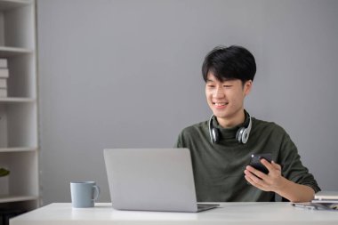 Yakışıklı genç bir ofis çalışanının portresi dikkatle bir sunum projesini ofisinde bir dizüstü bilgisayarla nasıl yapacağını araştırıyor...