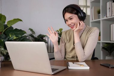 Asyalı üniversite öğrencisi evde oturup bilgisayarlarında bir video programı kullanarak ders çalışıyor...