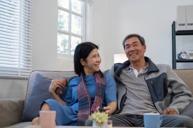 60 'lı yaşlarındaki emekli Asyalı çift boş zamanlarını birlikte oturma odasında televizyon izleyerek geçiriyor...