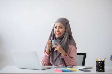 Ofisteki çalışma masasında sohbet ederken tesettüre giren gülümseyen Müslüman iş kadını...
