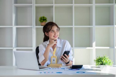 Asyalı kadın ofis çalışanı pencereden dışarı bakıyor işini düşünüyor ve gelecek için planlar yapıyor...