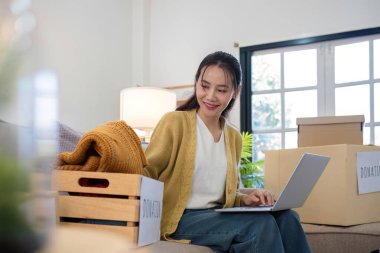 Genç bir kadın kullanılmayan giysileri ayırır ve onları hava kirliliğini azaltmak ve çevreyi korumak için bağış veya geri dönüşüme hazırlar...