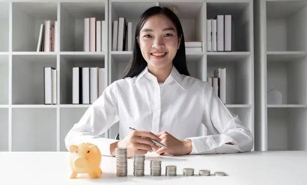 Beautiful accountant with coins and piggy bank placed on the table Money saving concept.
