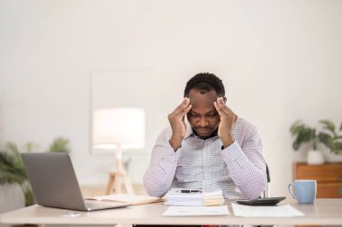 Genç bir Afrikalı işadamı baş ağrısı hisseder. Ofis odasındaki beyaz ahşap bir masada dizüstü bilgisayarla çalışırken strese girdim..