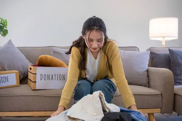 A young woman separates unused clothes and prepares them for donation or recycling in order to reduce air pollution and protect the environment..