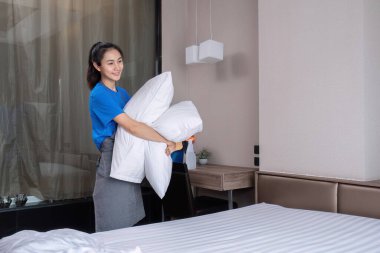 Güzel temizlikçi kadın. Temizle ve yatağın üzerindeki yatağı özenle hazırla...