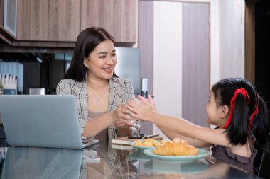 Genç, bekar bir anne, kızıyla birlikte laptopuyla evde çalışırken atıştırıyor...