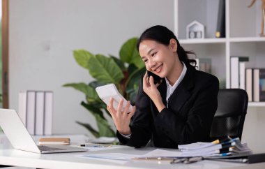 Güzel muhasebeci telefonda konuşuyor, finansal rakamları hesaplıyor ve şirketin vergilerini hesaplıyor...