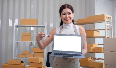 Küçük bir KOBİ işletmesi sahibi elinde beyaz ekranlı bir dizüstü bilgisayar tutuyor. Ofisinizde küçük işletme bilgilerini kaydetmek için bir dizüstü bilgisayar kullanın..